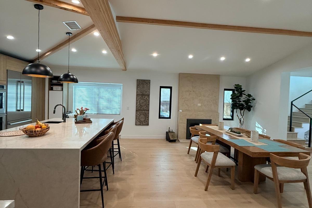 Island with counter seating and a dining table under a vaulted beamed ceiling